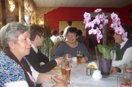 Uczestnicy wycieczki ZKP Linia siedzą przy stole, rozmawiając i pijąc napoje.