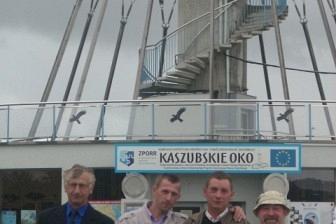 Czterech mężczyzn stoi przed wieżą widokową Kaszubskie Oko w Gniewinie.