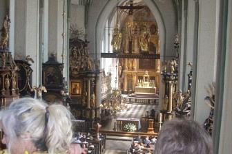 Wnętrze kościoła lub sali z ludźmi podczas uroczystości, widok na ołtarz.