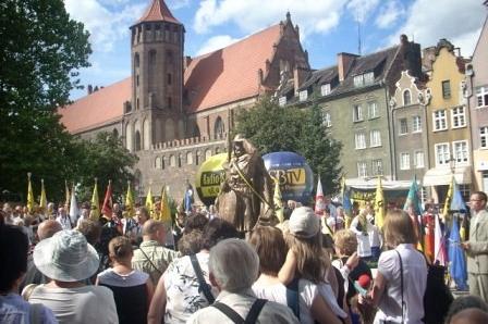 Tłum gapiów podczas odsłonięcia pomnika Świętopełka na tle zabytków Gdańska.