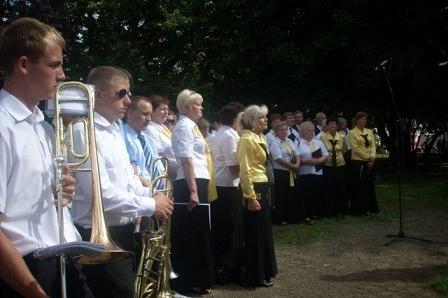 Członkowie orkiestry dętej stojący z instrumentami podczas odsłonięcia pomnika.