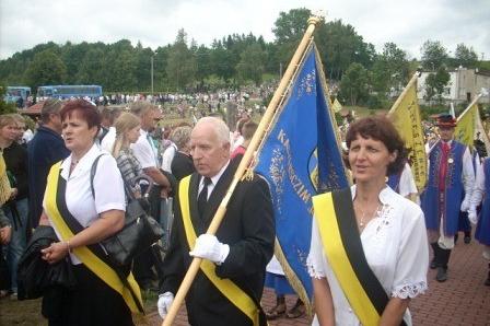 Uczestnicy odpustu w Sianowie w procesji z chorągwią i szarfami.