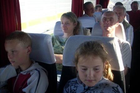 Dzieci i dorośli jadą autobusem na wycieczkę.