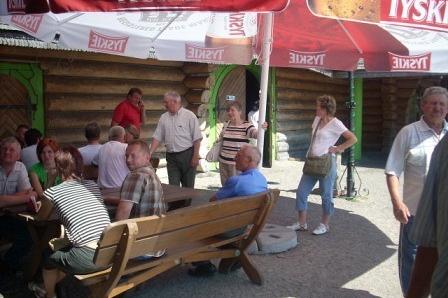 Uczestnicy wycieczki relaksują się w ogródku pod czerwonym parasolem Tyskie.