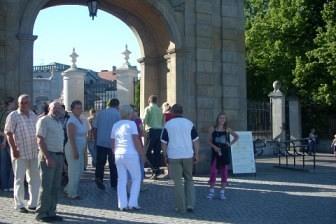 Grupa turystów pod historyczną bramą w słoneczny dzień wycieczki.