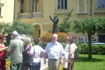Uczestnicy wycieczki ZKP O/Linia stoją przed okazałym budynkiem w słoneczny dzień.