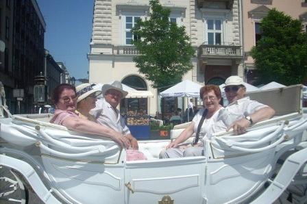 Uczestnicy wycieczki radośnie pozują w białej dorożce, zwiedzając miasto.