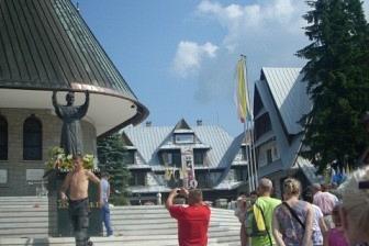 Uczestnicy wycieczki ZKP O/LINIA, z osobą w czerwonym, podziwiający widoki pod błękitnym niebem.