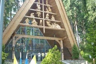 Góralski drewniany budynek z trójkątnym dachem wśród drzew.