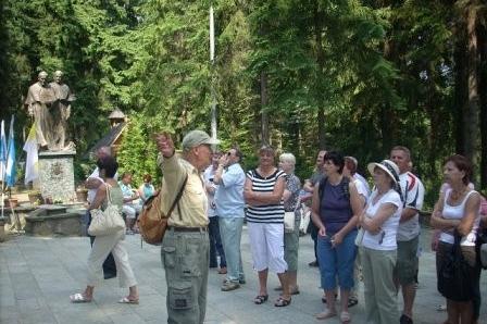 Grupa turystów słucha przewodnika przy pomniku podczas wycieczki ZKP O/Linia.