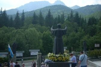 Grupa ludzi obok monumentu z widokiem na zalesione góry podczas wycieczki ZKP.