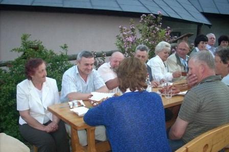 Grupa osób siedzi przy stole na zewnątrz, ciesząc się wspólnym posiłkiem podczas wycieczki ZKP.