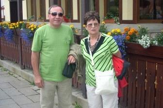 Dwie osoby uśmiechają się do zdjęcia na tle budynku podczas wycieczki.