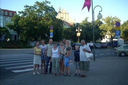 Grupa uczestników wycieczki ZKP O/LINIA na tle miejskiego krajobrazu z flagą.