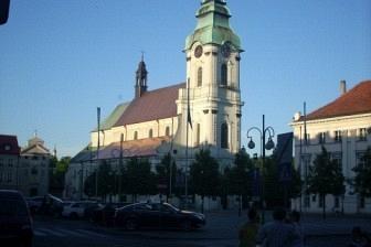Widok na kościół z wieżą i zielonym hełmem pod błękitnym niebem podczas wycieczki.