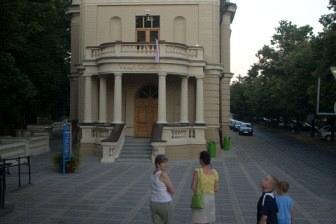 Klasyczny budynek z kolumnami i turystami spacerującymi po placu.