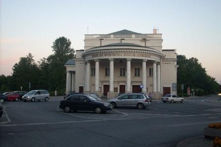 Teatr im. Adama Mickiewicza w Częstochowie z samochodami na placu przed nim.