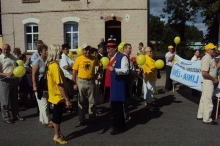 Grupa ludzi w żółtych strojach i czapkach na Zjeździe Kaszubów w Pucku.