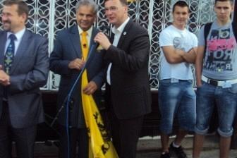 Oficjele i uczestnicy Zjazdu Kaszubów w Pucku, mężczyzna z żółtym szalem przemawia.