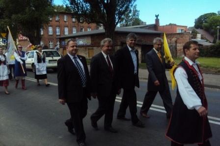 Uczestnicy Zjazdu Kaszubów w garniturach i tradycyjnym stroju idą ulicą w Pucku.
