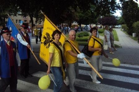 Grupa ludzi z żółtą flagą kaszubską z Gryfem i błękitno-białą flagą na zjeździe.