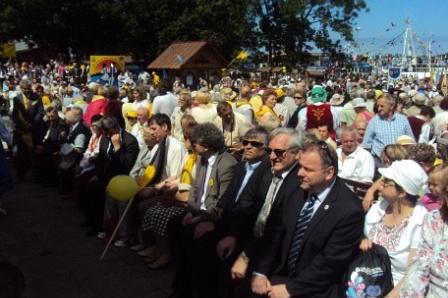 Uczestnicy Zjazdu Kaszubów w Pucku siedzą na świeżym powietrzu.