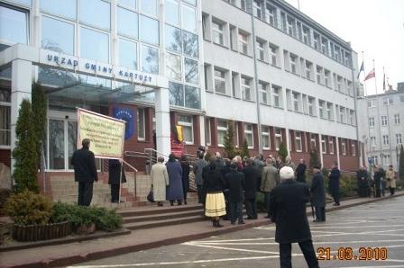 Uczestnicy Dnia Jedności Kaszubów przed budynkiem w Kartuzach, niektórzy z transparentami.