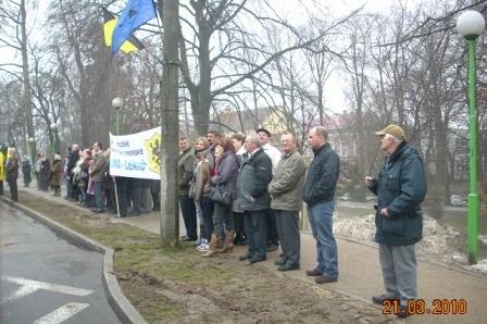 Grupa ludzi z flagą kaszubską gromadzi się w parku podczas Dnia Jedności Kaszubów.