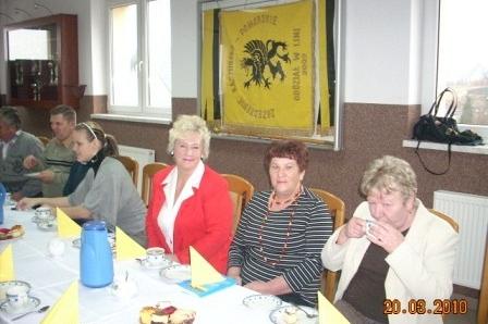 Uczestnicy szkolenia ZKP w Lini siedzą przy stole z napojami, w tle kaszubski sztandar.