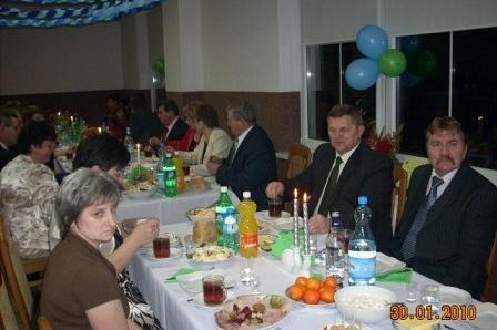 Uczestnicy karnawałowej zabawy ZKP O/Linia siedzą przy suto zastawionym stole z balonami.