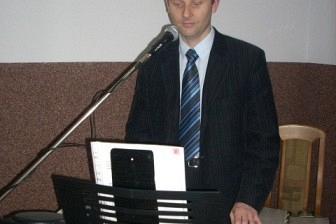 Mężczyzna w garniturze wygłasza przemówienie na karnawałowej imprezie ZKP.