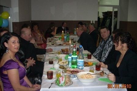 Ludzie na zabawie karnawałowej siedzą przy suto zastawionym stole.