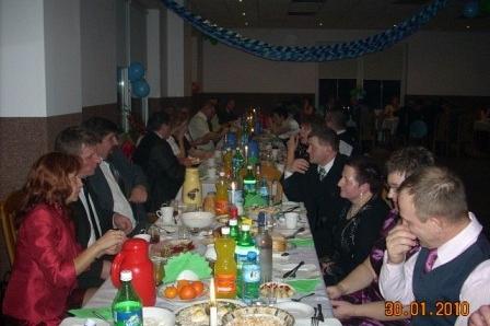 Uczestnicy zabawy karnawałowej siedzą przy suto zastawionym stole.