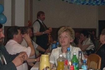 Uczestnicy zabawy karnawałowej siedzą przy suto zastawionym stole, widoczne napoje i dekoracje.