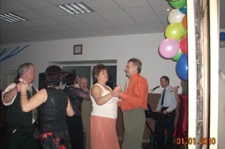 Tańczący ludzie na zabawie karnawałowej, w tle kolorowe balony.