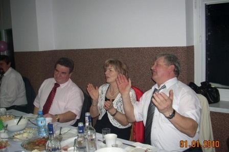 Goście zabawy karnawałowej śmieją się i klaszczą przy stole.