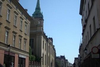 Widok ulicy miasta z zabytkową wieżą wśród kamienic w słoneczny dzień wycieczki.