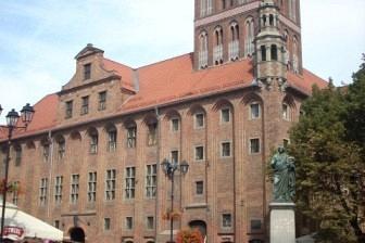 Widok na toruński Ratusz Staromiejski z wieżą, podziwiany przez uczestników wycieczki.
