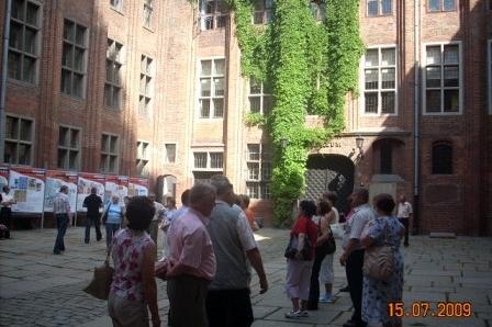 Wycieczka na dziedzińcu zabytkowego budynku z cegły, z pnączem na ścianie.