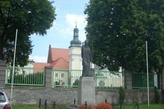 Widok na ulicę, wysokie drzewa i zabytkowy budynek z wieżą podczas wycieczki.