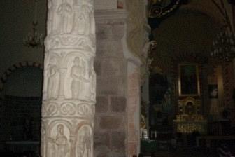 Wnętrze kościoła z rzędami drewnianych ławek i masywnymi kolumnami.