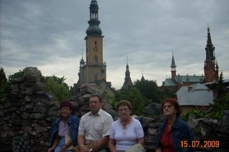 Uczestnicy wycieczki siedzą na tle wysokich wież bazylik i kościołów.
