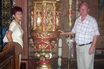 Dwóch uczestników wycieczki przy złotej, zdobionej monstrancji w świątyni.