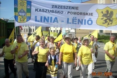 Uczestnicy Zjazdu Kaszubów maszerują z transparentem Przyjazny Partnerski Program Linia-Łenio.