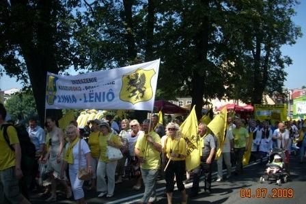 Ludzie z żółtymi flagami i transparentem na Zjeździe Kaszubów w Bytowie.
