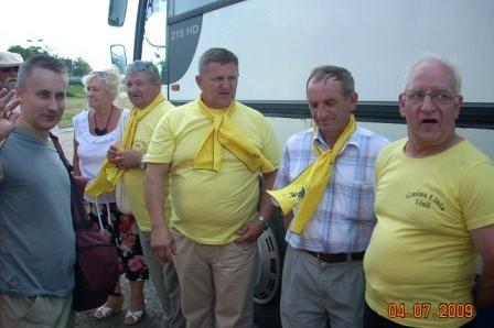 Kaszubi w żółtych koszulkach i szalikach stoją obok autobusu.