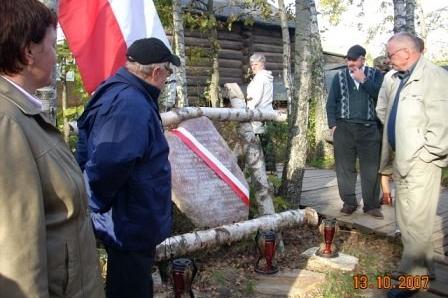 Grupa osób podczas wycieczki w Szymbarku, mężczyzna prezentuje zwój pod polską flagą.
