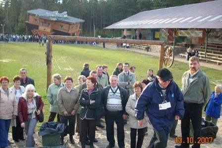 Grupa uczestników wycieczki ZKP w Szymbarku przed regionalnymi budynkami.