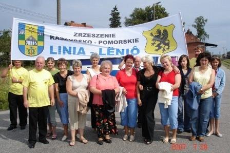 Grupa mieszkańców Gminy Linia stoi pod banerem Zjazdu Kaszubów.