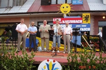 Mężczyźni na podium z rowerem i balonem słońcem, festyn sportowy na Kaszubach.